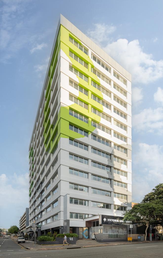 A tall building seen from the corner of two streets. Blue skies with a few clouds in the background.