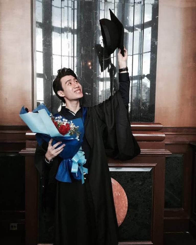 Malaysian graduate holding flowers and holding his cap up to the sky