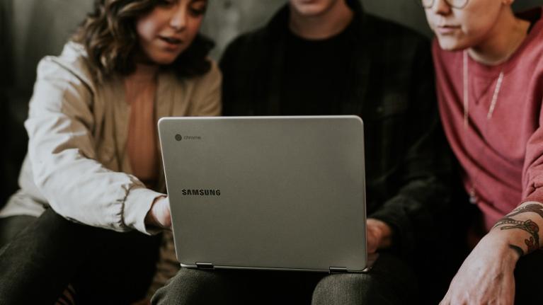 three teenagers looking at laptop