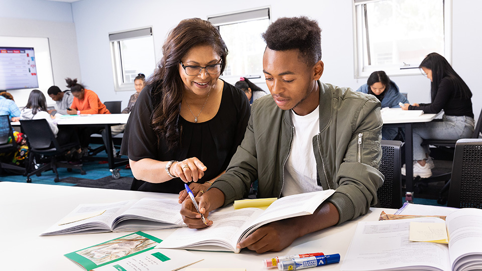 Benjamin Bwenge studying in the classroom with help from a teacher.