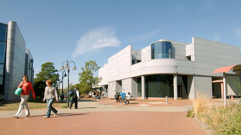 Students walk outside the Victoria University St Albans Campus on a sunny day.