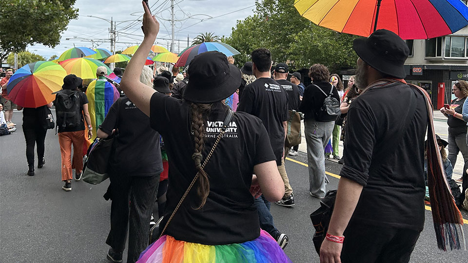 VU students and staff marching in the rain with rainbow umbrellas.