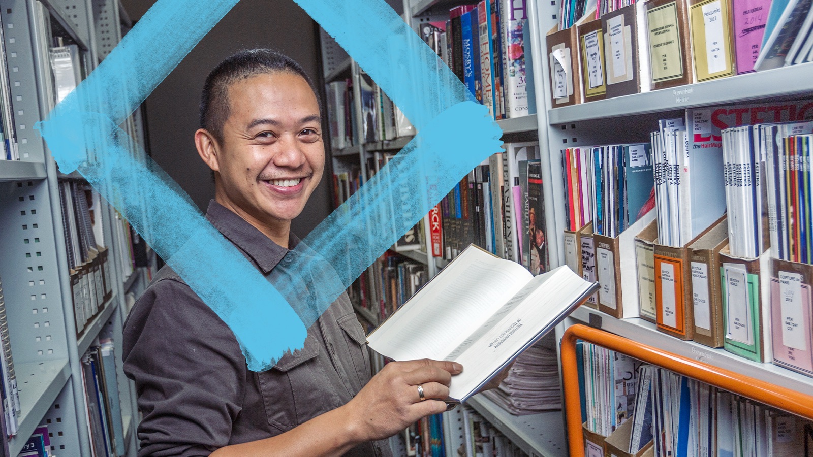 Smiling student with an open book in the library