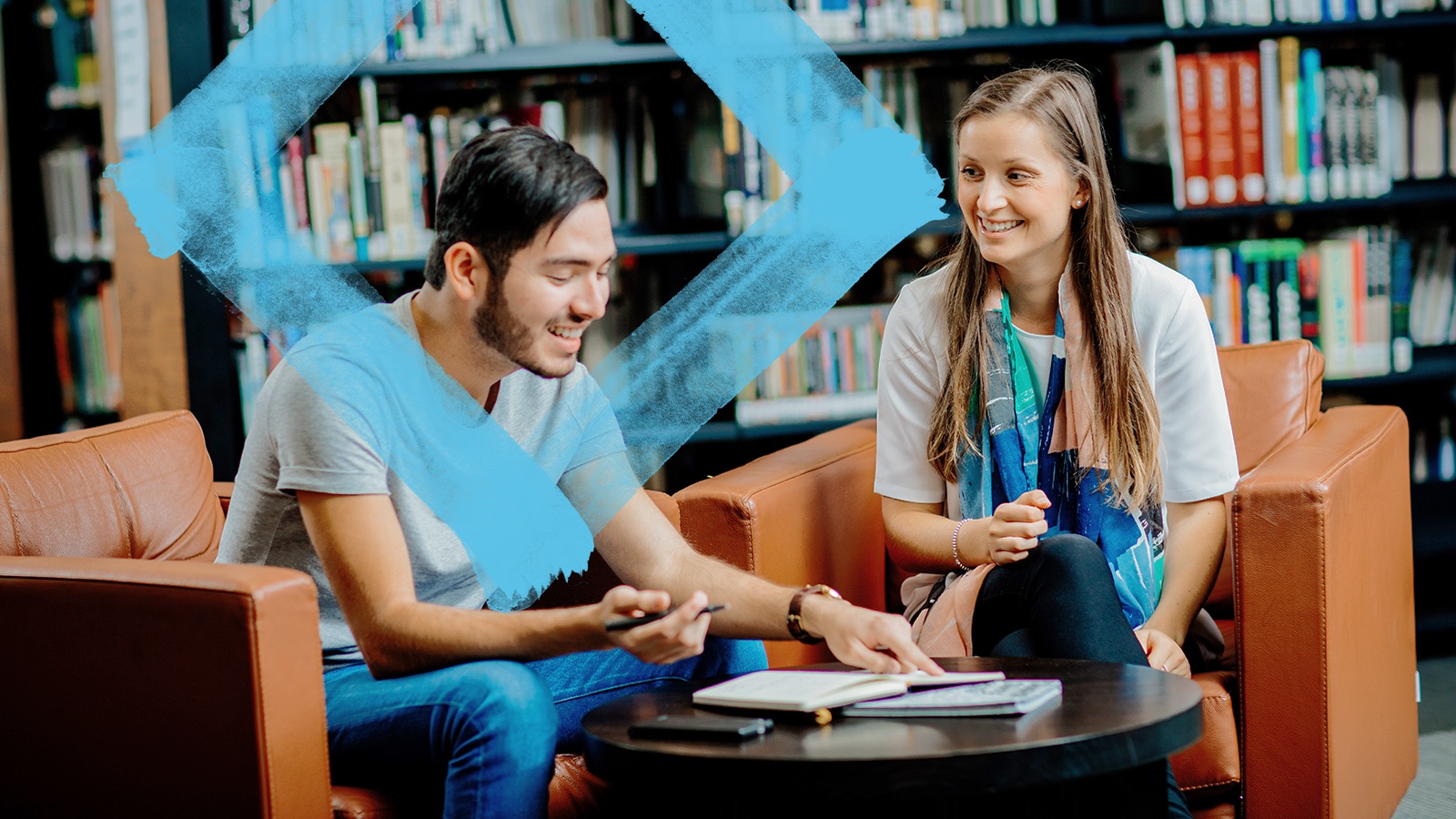 Two students sitting in the library, engaged in conversation