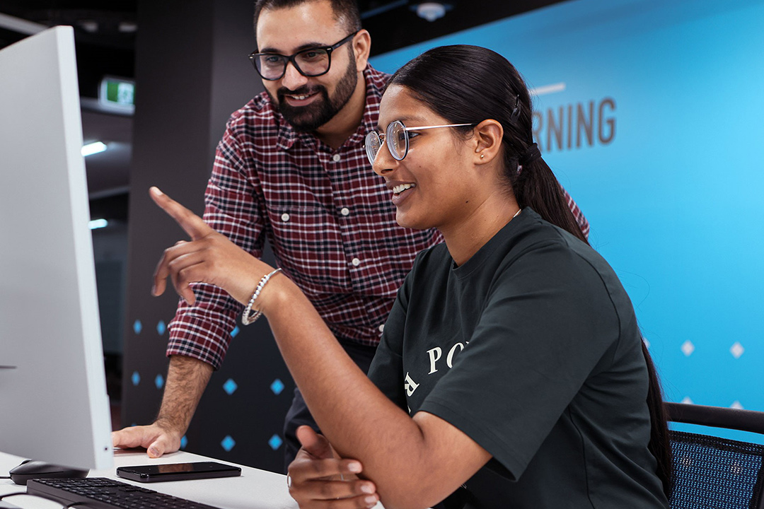 A smiling woman receives advice for computer-based work