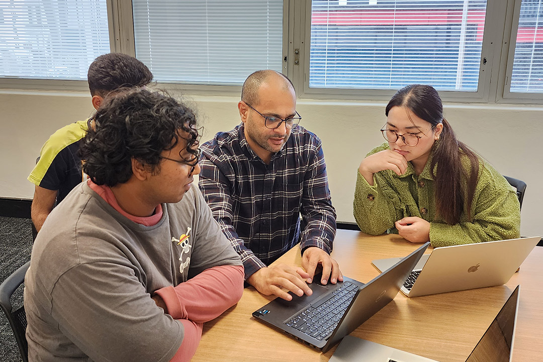 A group of students around a laptop