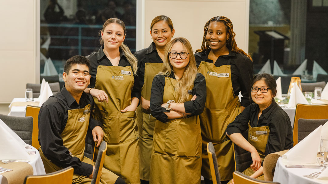 Hospitality students standing in VenU restaurant, smiling at the camera