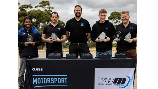 5 men in Victoria University T-Shirts hold awards behind a stall that branded Motorsport VUM