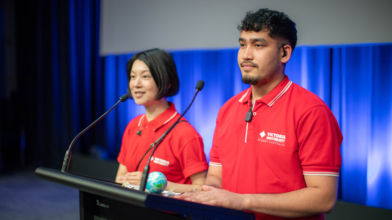 Two student mentors standing on stage behind a podium