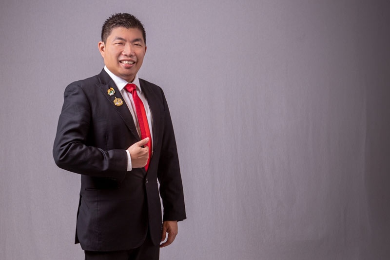 a smiling man in a professional black suit and red tie