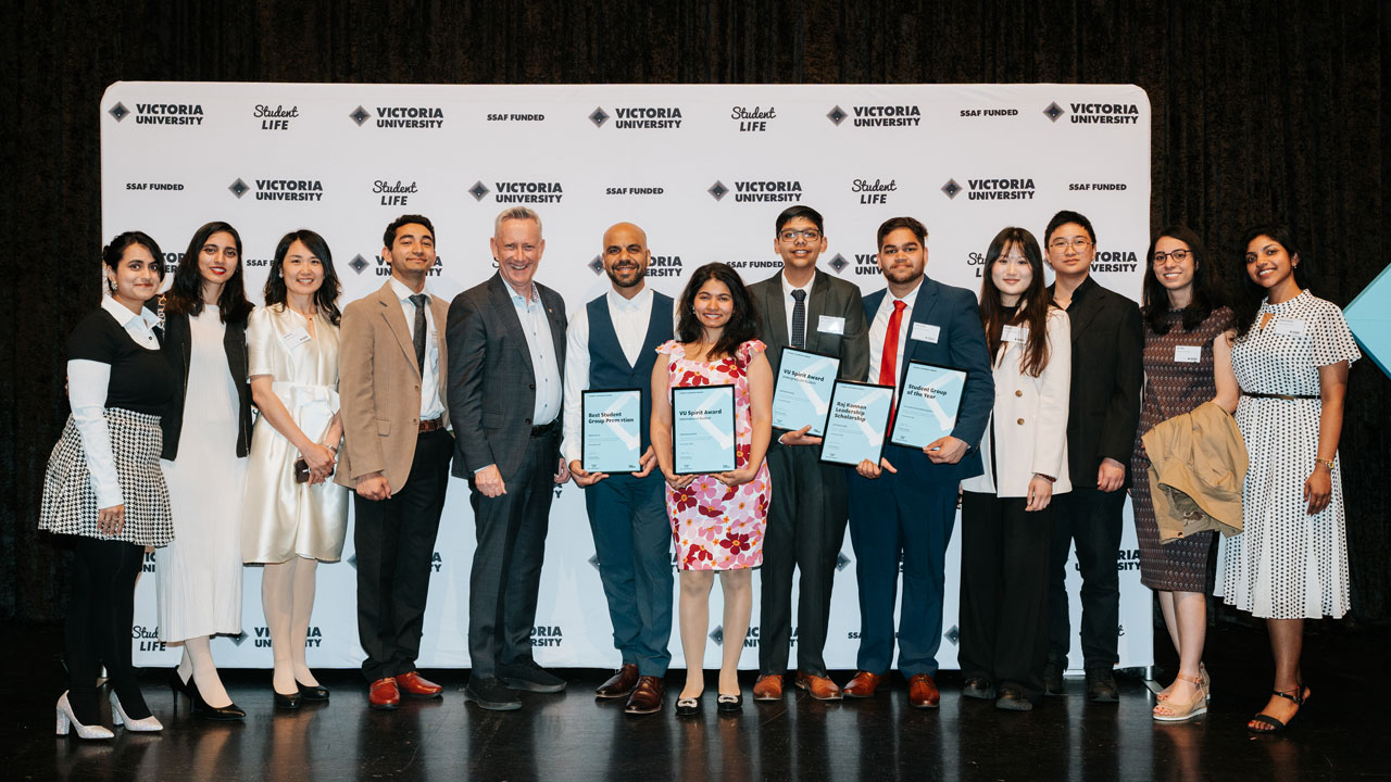 Students dressed in formal wear holding awards and posing for a photo.