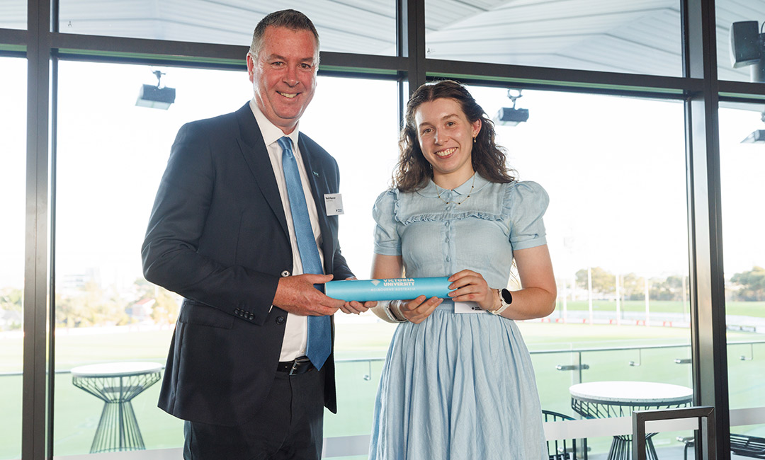 A young woman in a summer dress is presented an award 