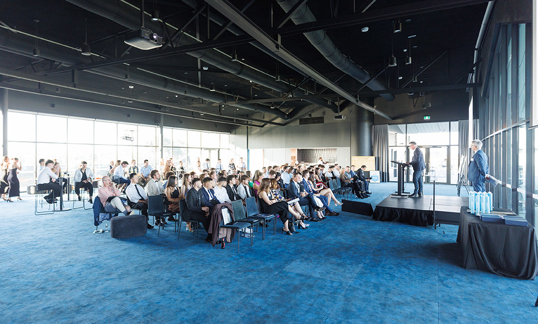 An awards presentation in a modern room with a mid-sized seated audience