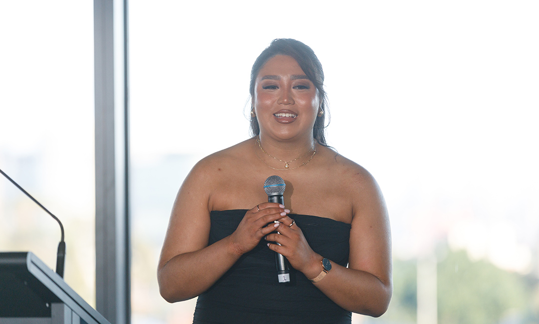 A young woman, strong-looking woman in a strapless dress holds an award