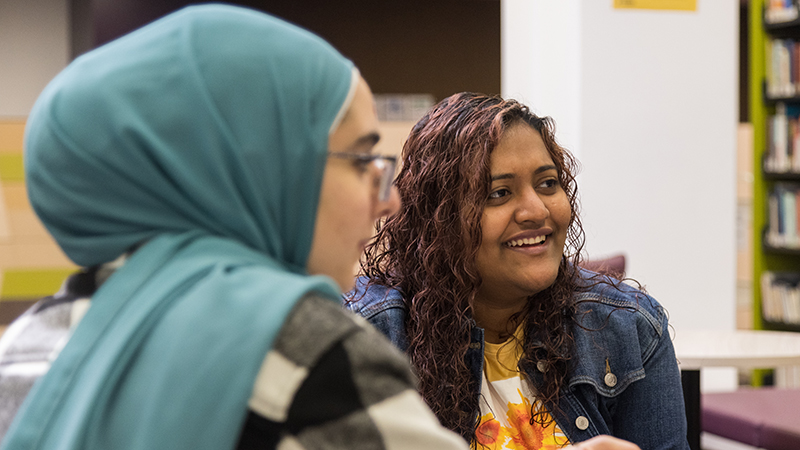 two students, multicultural, smiling during library study group