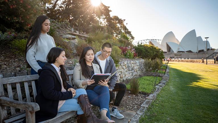 Students read in the park, with Sydney Opera house in background