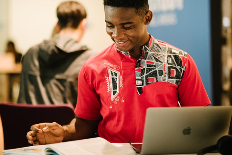 student with laptop and book