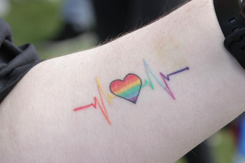 Tattoo of a rainbow heart on a forearm.