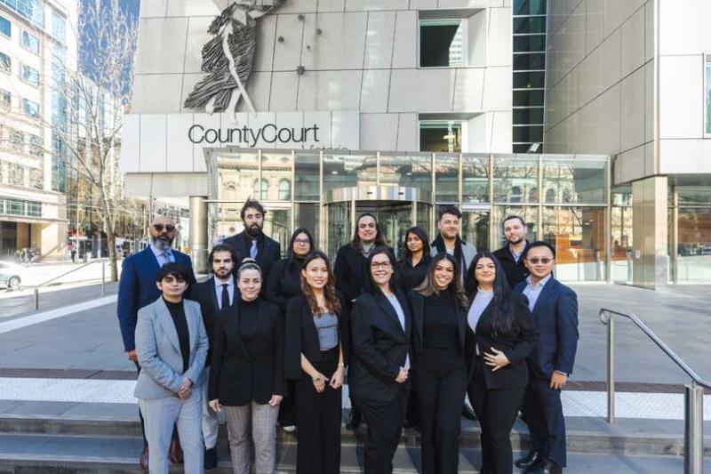 A group of 15 barrister shadowing program participantx, standing and smiling on the steps outside the County Court. 