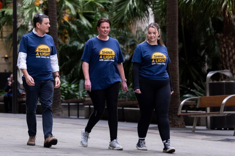 Three people walking with shirts that say "Shine a light with every step"