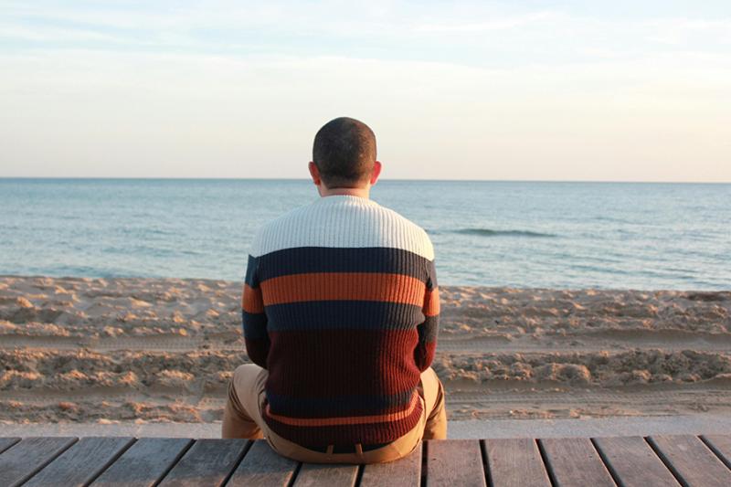 A man looks out over a lonely beach