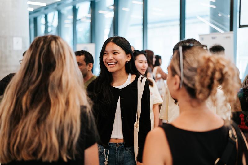 A group of young people interact happily in a bright, modern building