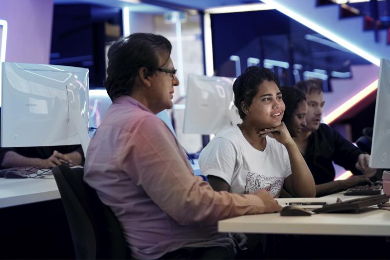 A student and a teacher sitting in a computer lab looking at a computer.