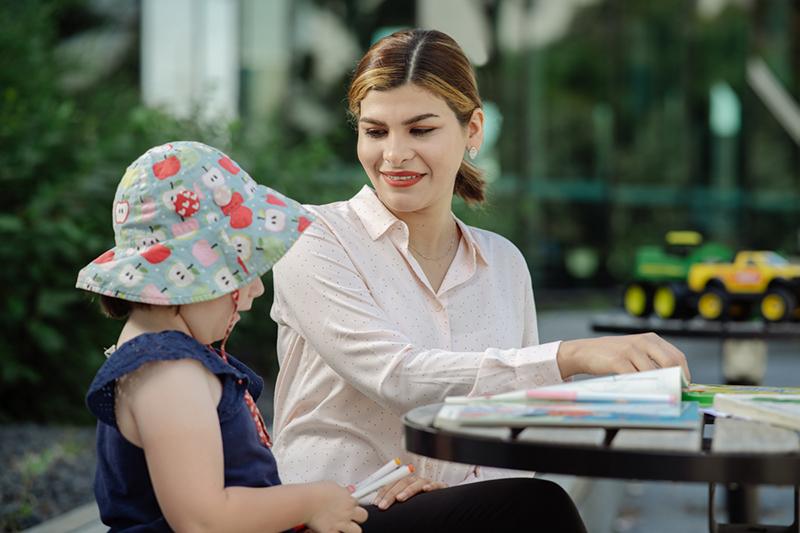 Early childhood teaching student smiles at kindergarten child