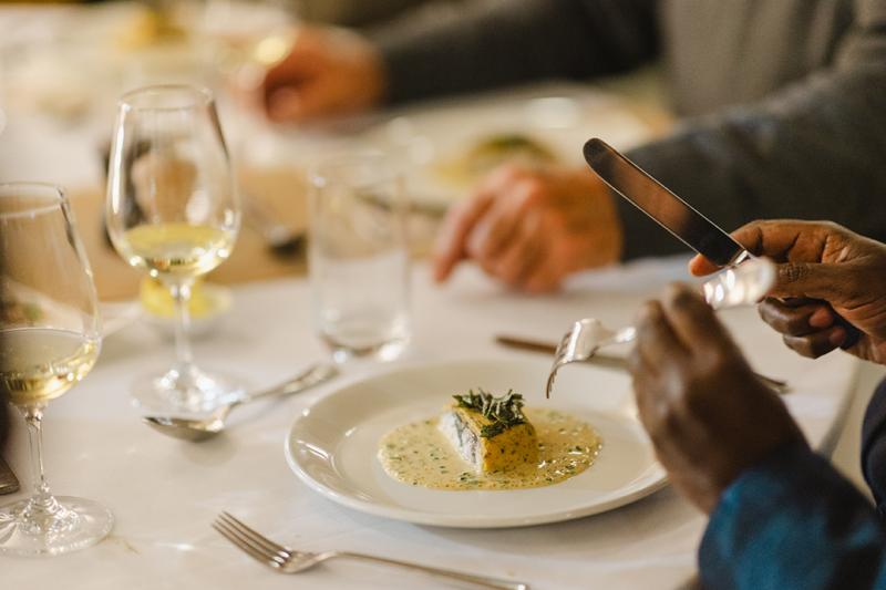 A formal, sophisticated dinner with glass of white wine served on a table with white cloth