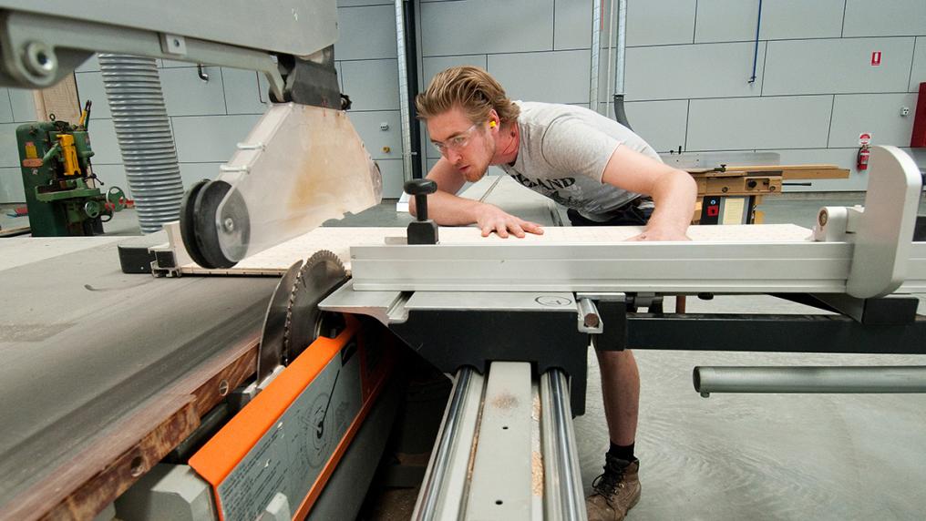 Young man using manufacturing machinery 