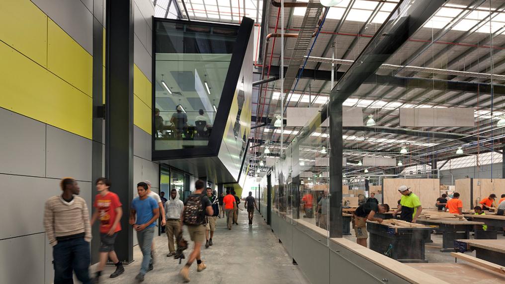 large, modern warehouse-style space with people in trade uniform, doing carpentry work