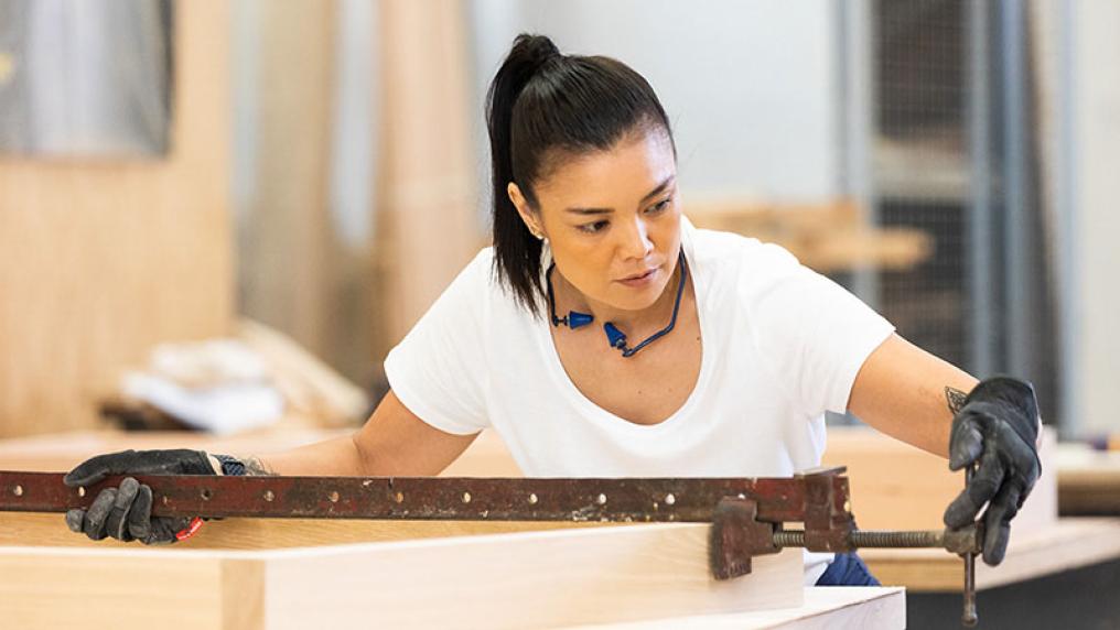 Female carpentry student using tools in to build a cabinet