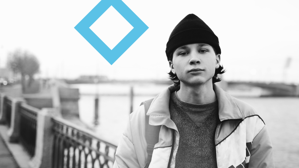 A VU student in a beanie stands next to the VU branded blue diamond.
