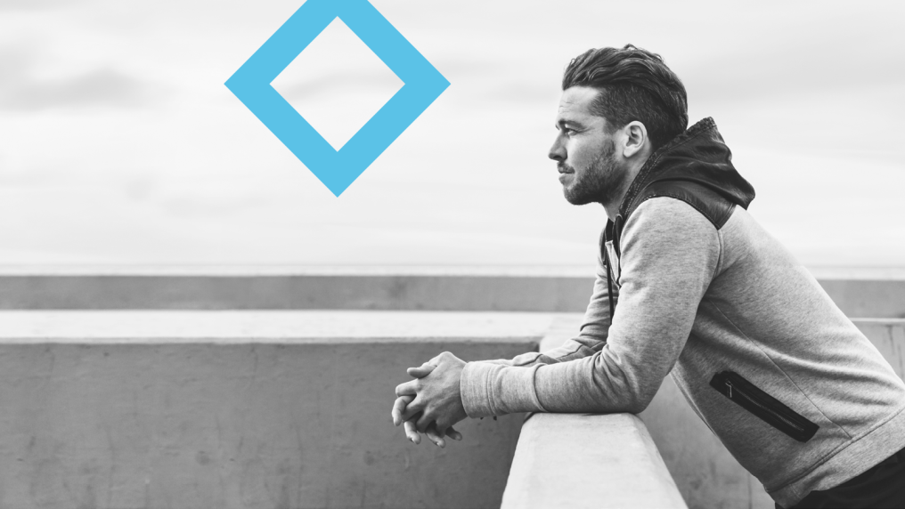 A student gazes out from a balcony, with the VU blue diamond ahead of them.
