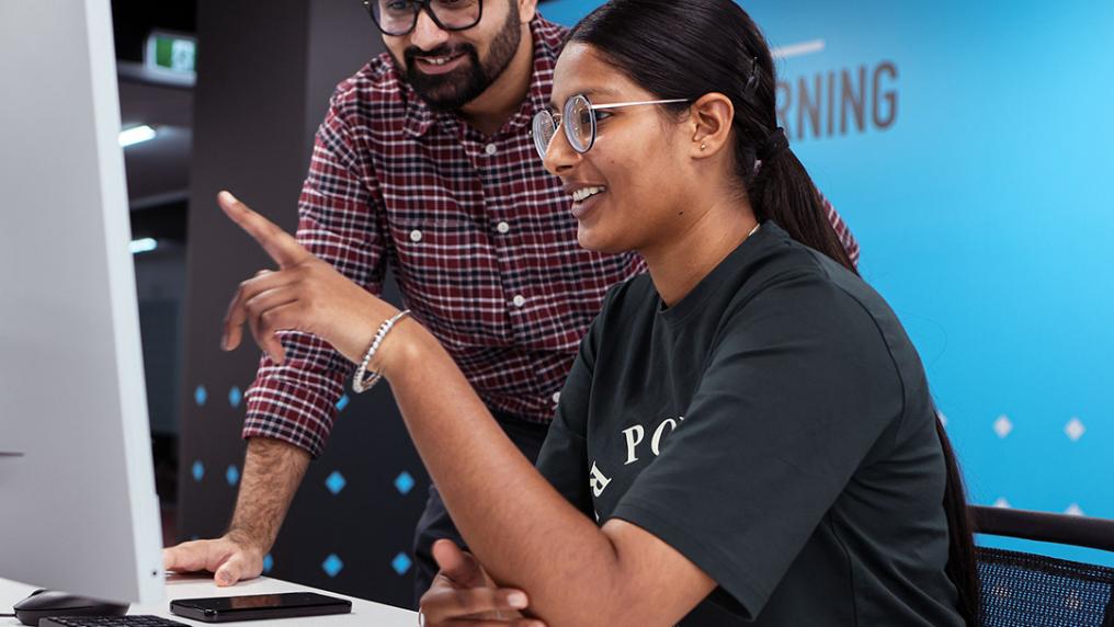A smiling woman receives advice for computer-based work