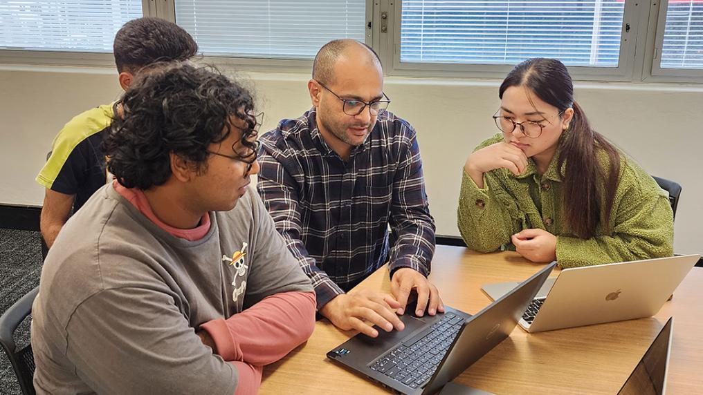 A group of students around a laptop