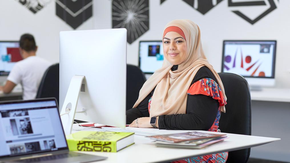 A young woman in a hijab behind a large screen in a modern design studio