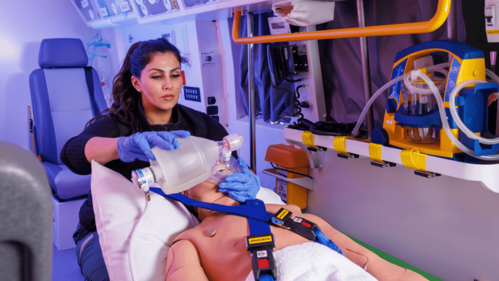 paramedicine student treating a manikin in an ambulance simulation pod