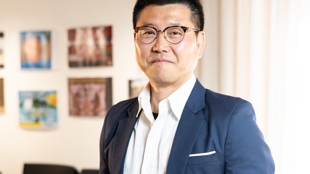 A man in a neat suit poses for a photo indoors