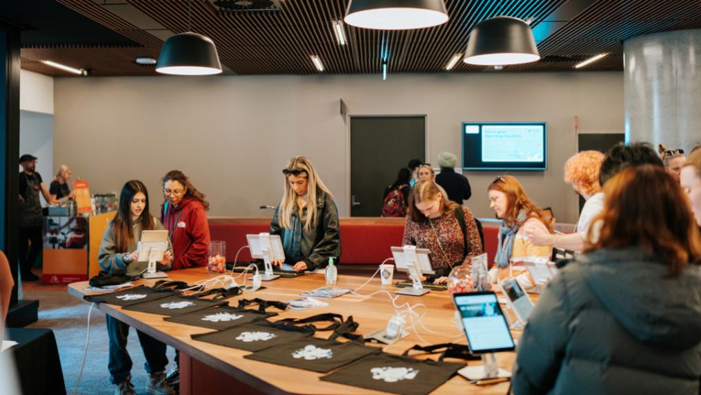 Students stand at a large table using tablets to apply for VU Early Entry program.