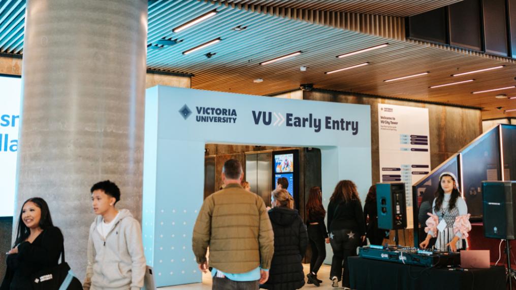 People walking towards large VU Early Entry archway at City Tower campus.   