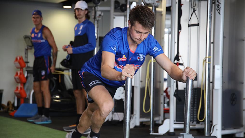a young man in red and blue sport uniform uses gym with specialised equipment