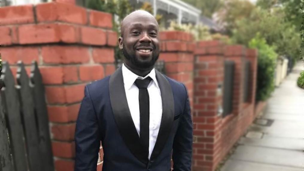 Diploma of counselling student in a suit, outside, smiles at the camera