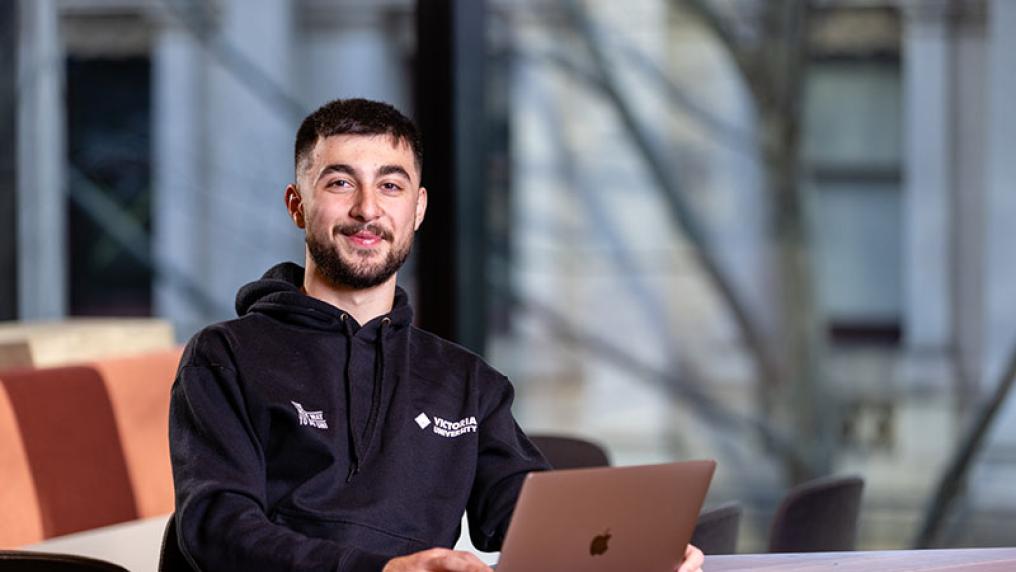 Male student with laptop studying in the VU City Tower communal study space 